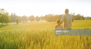 Father and son looking across their grain field at sunrise.