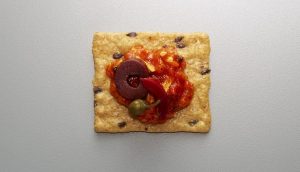 Crunchmaster Multi-Grain cracker with olives on top.