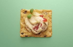 Crunchmaster cracker with a cheesy spread on top.