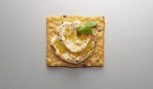 Crunchmaster Multi-Grain cracker topped with hummus.
