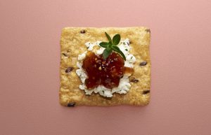 Crunchmaster cracker with cheese and jam on top.
