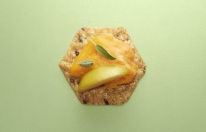 Crunchmaster cracker with cheese and apple on top.