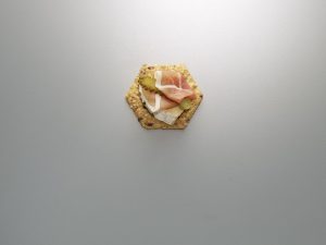 Crunchmaster Multi-Seed cracker with brie cheese and prosciutto on top.