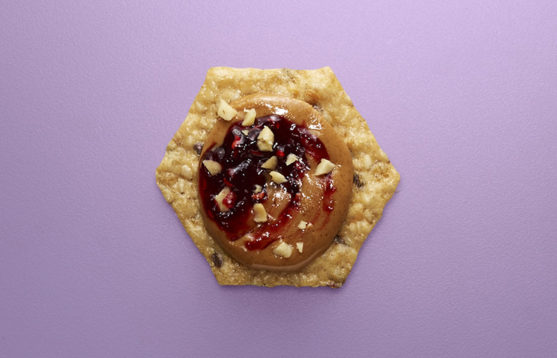 Crunchmaster cracker with peanut butter and jelly on top.